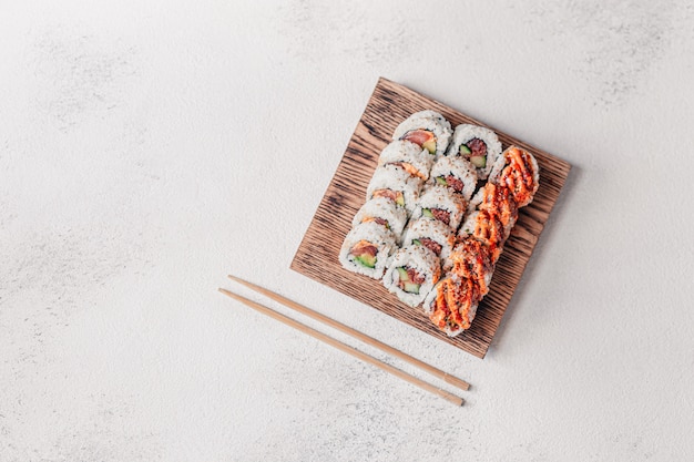 Photo fancy sushi rolls serving on a wooden board and a chop sticks.