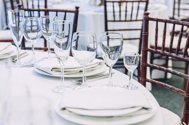 レストランの豪華なインテリアの背景にナプキングラスとディナーに設定された豪華なテーブル