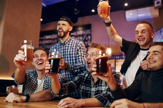 Fans cheer and shout Group of people together indoors in the pub have fun at weekend time