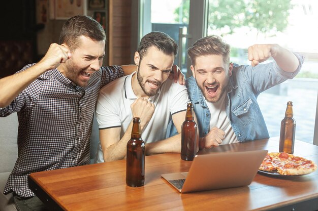 Fans kijken naar sportwedstrijden op laptop in het café en drinken bier