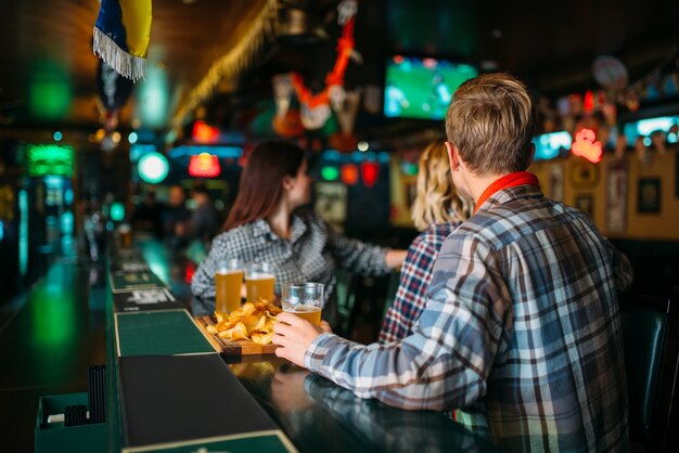 Fans with glasses of beer at counter in sports bar