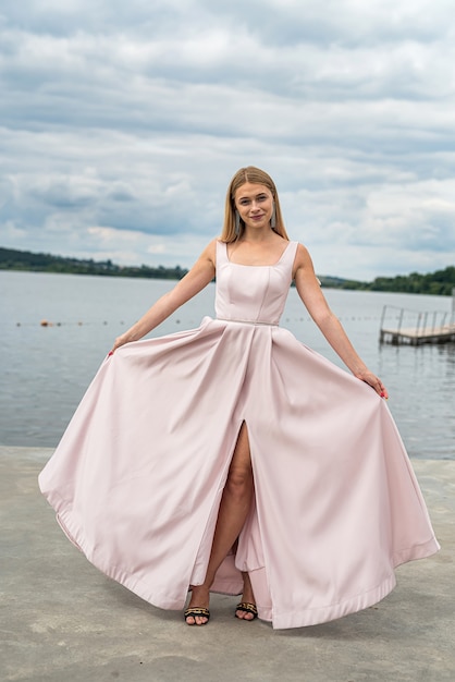 Foto fantasie charmante vrouw in elegante ping avondjurk ontspannen in de buurt van meer, zomertijd