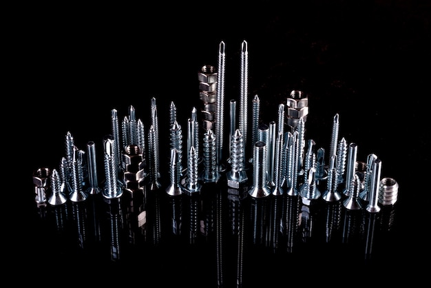 A fantastic city made of bolts, nuts, screws and self-cuts on a black background with reflection