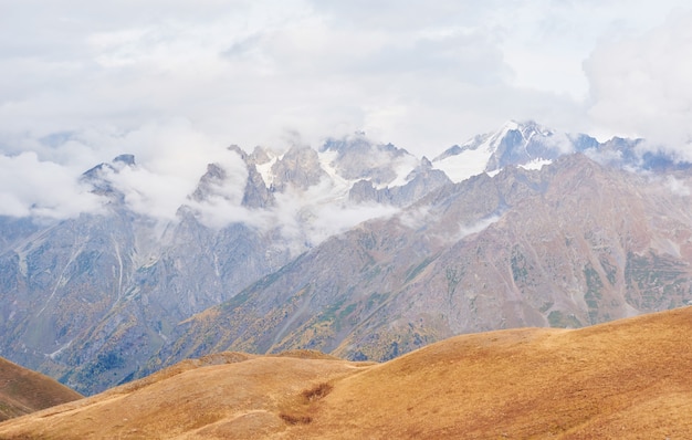 Фантастические заснеженные горы в красивых кучевых облаках. Главный Кавказский хребет. Тип Гора Ушба Мейер, Грузия