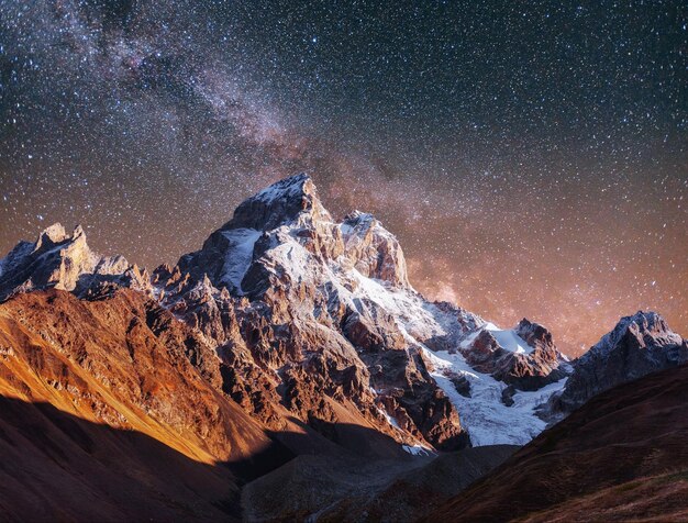 Photo fantastic starry sky autumn landscape and snowcapped peaks ma