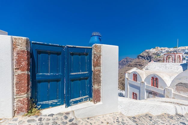 Fantastic travel background Santorini urban landscape. Blue door entrance stairs Mediterranean sea