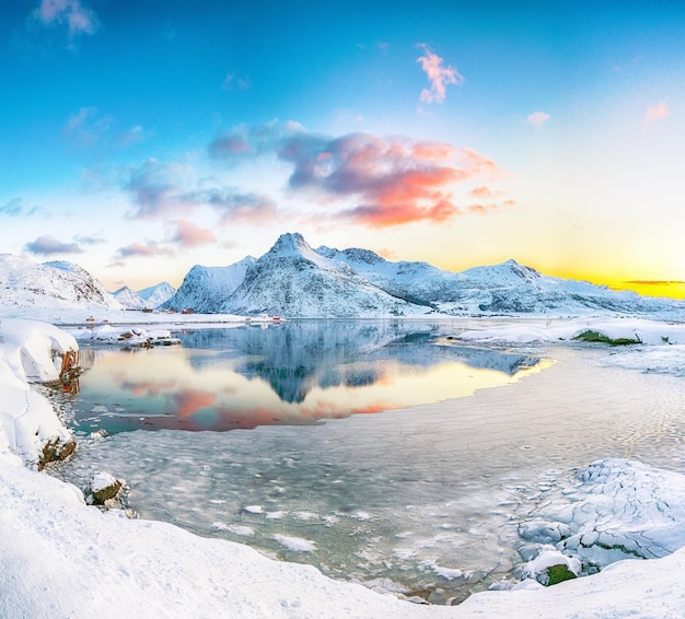Fantastische bevroren Flakstadpollen en Boosen-fjorden en reflectie in water tijdens zonsopgang met Hustinden-berg op de achtergrond op het eiland Flakstadoya
