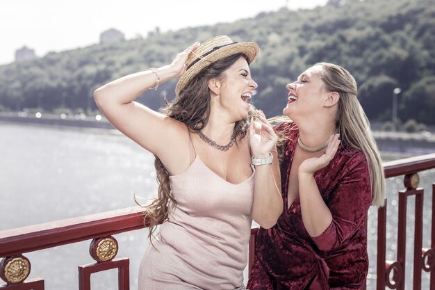 Fantastische dag. Positieve blije vrouwen lachen elkaar toe terwijl ze op de brug staan