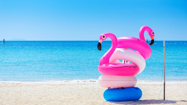 Fantasy Swim Ring and inflatable  flamingo balloon on the  sandy beach with blue sky and sea