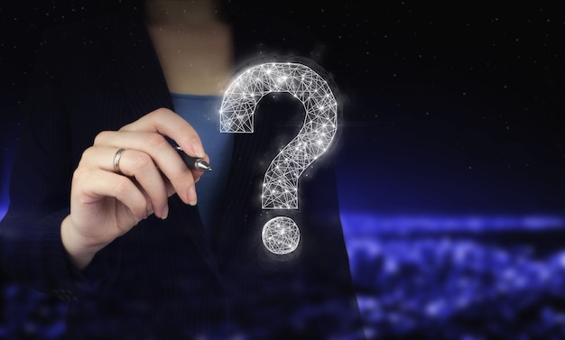 FAQ Concept image.Find answer online. Hand holding digital graphic pen and drawing digital hologram question mark sign on city dark blurred background. FAQ frequently asked questions concept.