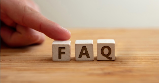 Faq concept Word faq on wooden cube with finger to shows letter f Frequently asked questions