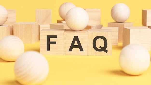 FAQ frequently asked questions text written on wooden blocks on yellow background