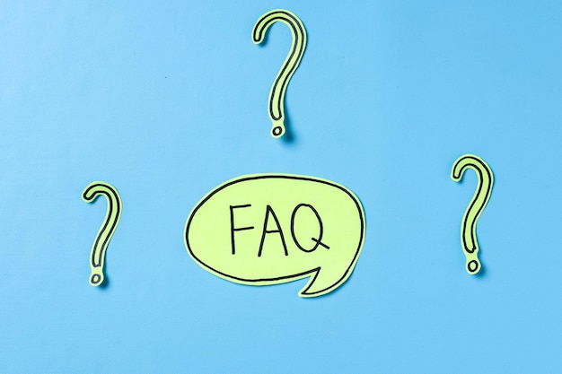 Photo faq lettering written on sticky note and question marks paper on blue background