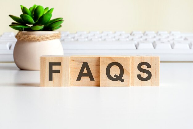 Faqs word made with wooden blocks. front view concepts, green plant in a flower vase and white keyboard on background