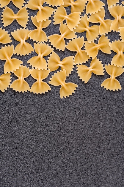 Farfalle Italiaanse pasta Vlinderdas Pasta op grijze achtergrond Verticale frame kopie ruimte
