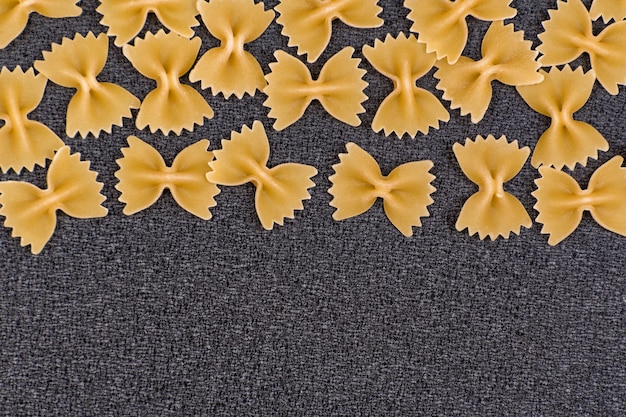 Итальянская паста Фарфалле. Паста галстук-бабочка на сером фоне. Скопируйте пространство.
