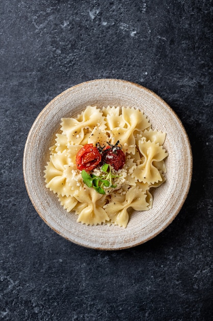 Farfalle pasta in a ceramic plate on a dark stone background view from above