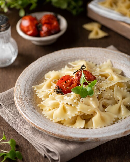 Farfalle pasta in a ceramic plate on a wooden surface, selective focus