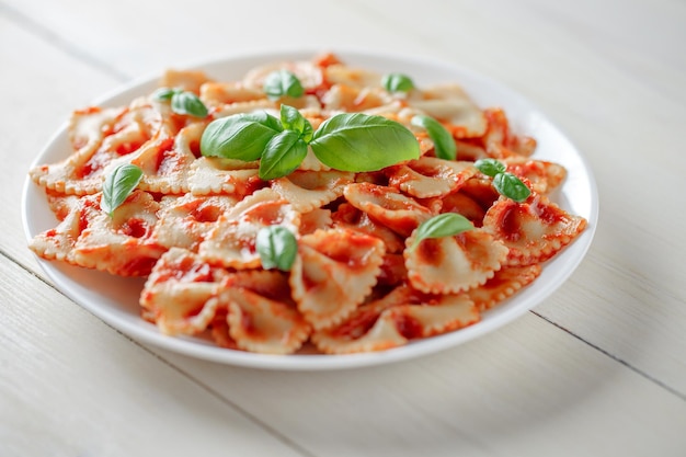 Farfalle pasta cooked with tomato sauce and basil in a white plate selective focus