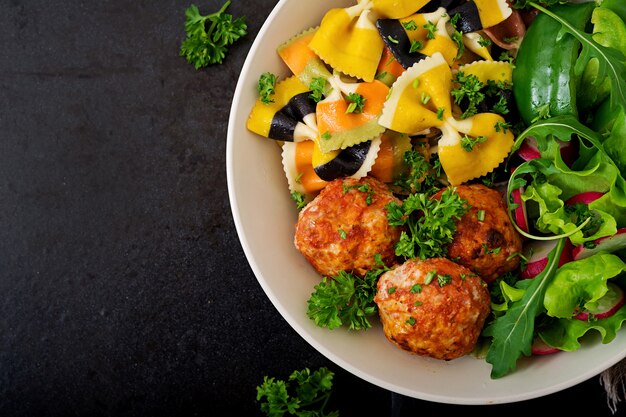 Farfalle pasta durum wheat with baked meatballs of chicken fillet in tomato sauce