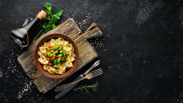 Farfalle pasta met groenten op het bord Bovenaanzicht Op een zwarte achtergrond Gratis kopieerruimte