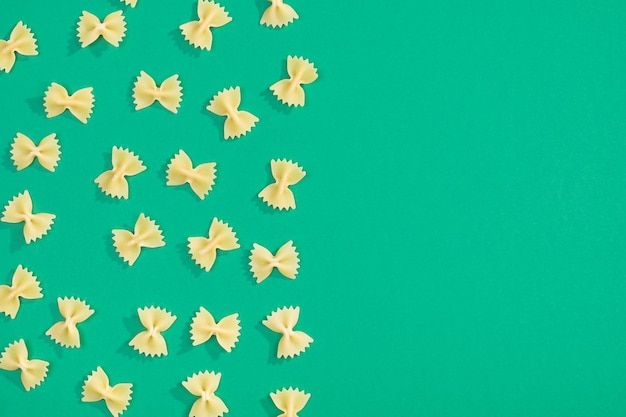 Farfalle pasta random flat lay pattern on green background