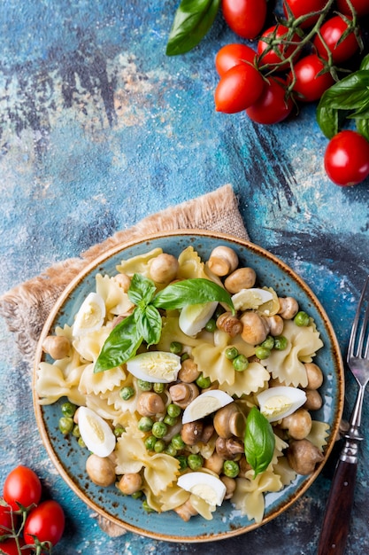 Farfalle pasta with champignon mushrooms, peas, egg and creamy sauce on a plate