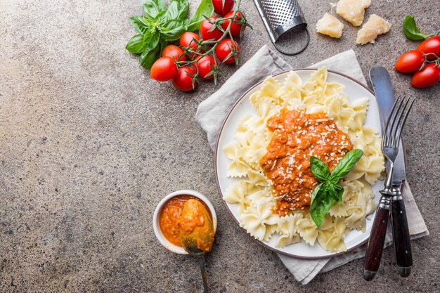 Farfalle pasta with homemade vegetarian tomato bolognese sauce, parmesan cheese and herbs on a plate