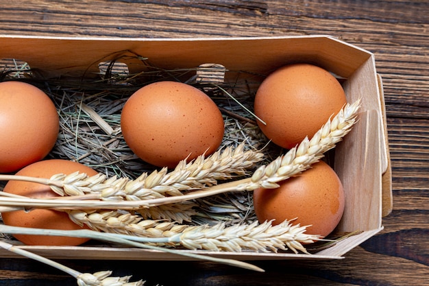 Farm brown eggs with straw in birch bark box wooden background close up