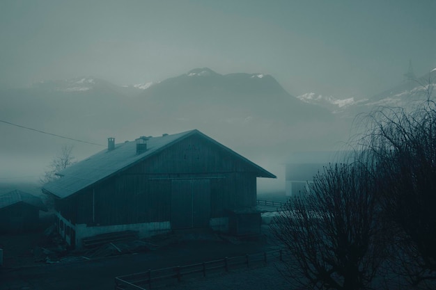 A farm building in the Austrian mountains is covered in thick fog