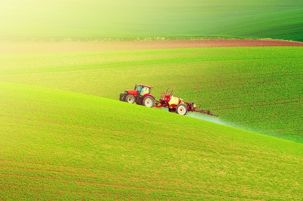 Farm machinery spraying insecticide to the green field agricultural natural seasonal spring background