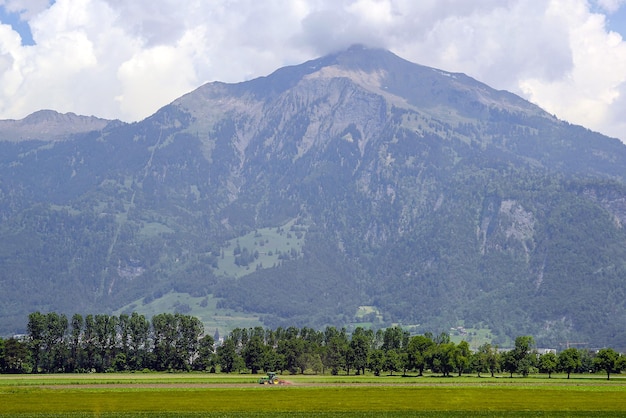 前景にトラクターがある山の中の農場