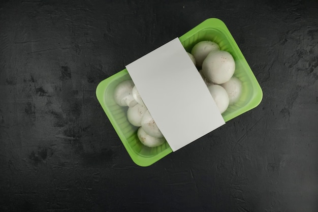 Farm mushrooms champignons in plastic packaging on a black background. top view. logo layout design.