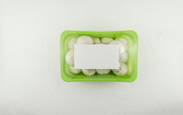 Photo farm mushrooms champignons in plastic packaging on a white background. top view. logo layout design.