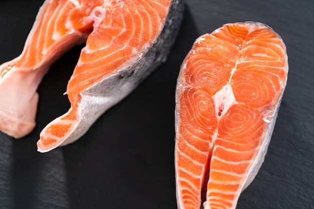 Farm-raised salmon steaks on a slate board.