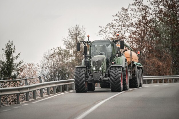 Farm tractor moving on the rural road near the farm