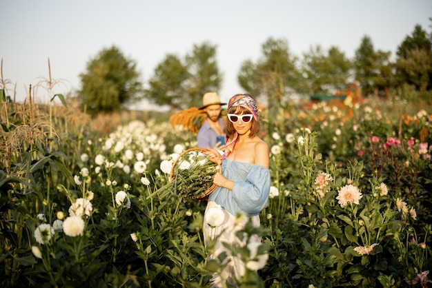 Работники фермы несут много свежесобранных цветов на ферме