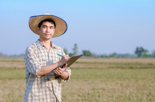 A farmer Asian man standing in a rice field with a paper board writing a message on the produce