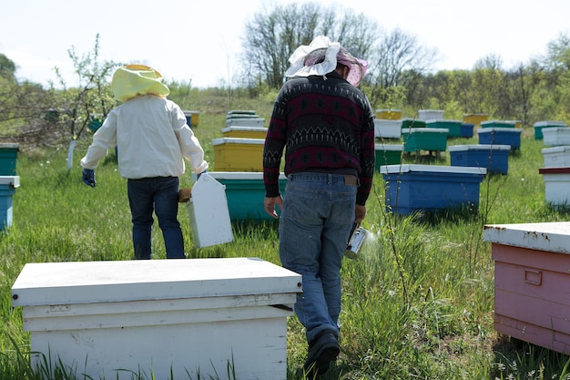 ミツバチの養蜂場の農家がワックスハニカムのフレームを持っている蜂蜜の収集のための計画された準備