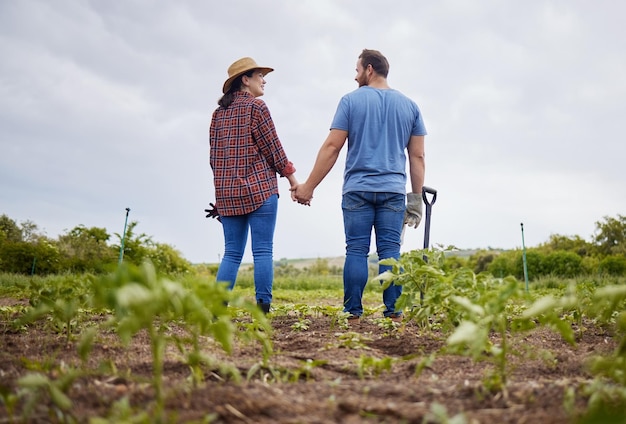 農夫の夫婦は、有機的または持続可能性のある農場または庭で、野菜作物や植物を使って農業の成長に満足しています 自然の中で男女が愛し、アウトドアを楽しみ、一緒に楽しんでいます