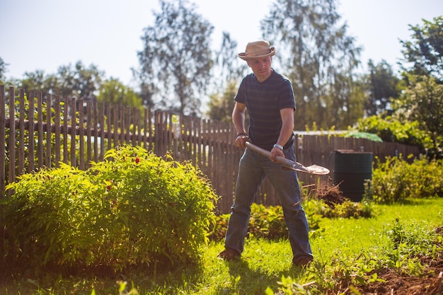 The farmer digs the soil in the vegetable garden Preparing the soil for planting vegetables Gardening concept Agricultural work on the plantation