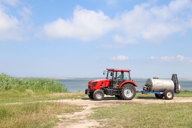 A farmer drives a tractor with a sprayer attached along the bay and reeds Agriculture