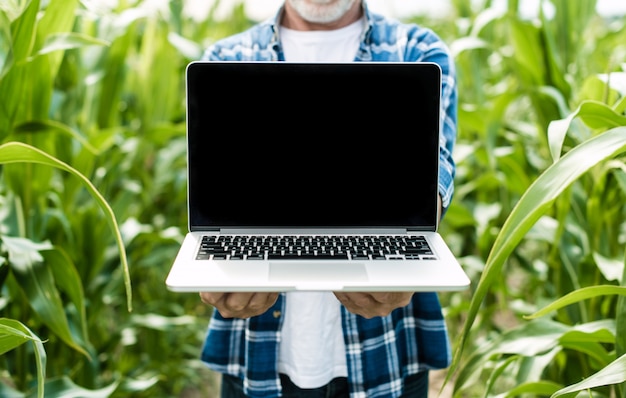 Farmer in the field showing laptop screen