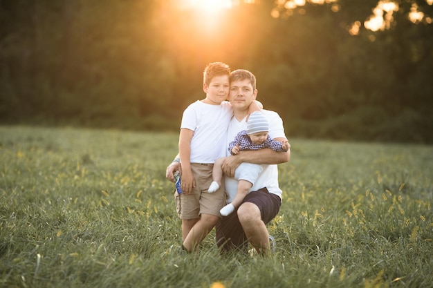 Foto contadino e i suoi figli davanti a un paesaggio agricolo al tramonto uomo e ragazzo in un campo di campagna paternità vita di campagna agricoltura e stile di vita di campagna