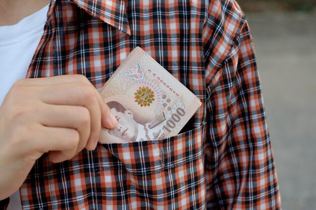 Farmer hold Thailand banknote money in shirt pocket