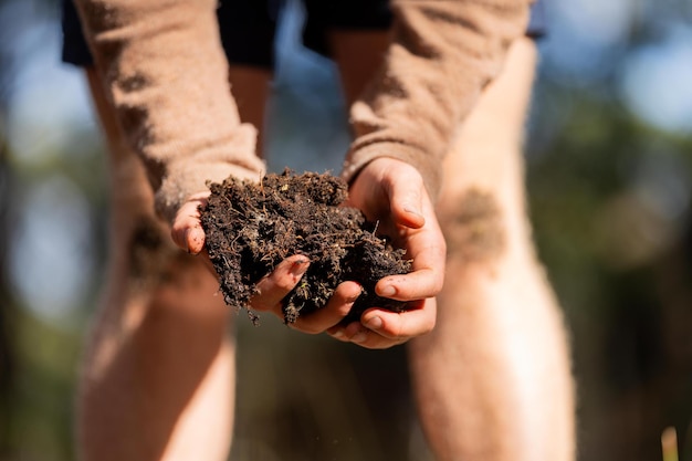 Photo farmer holding soil in hand and pouring soil on ground connected to the land and environment soil agronomy in australia soil heath study