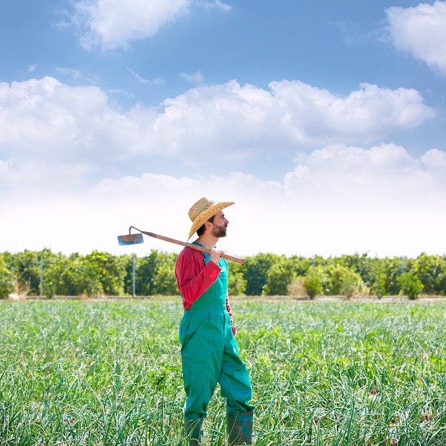 Farmer man with hoe looking at his field