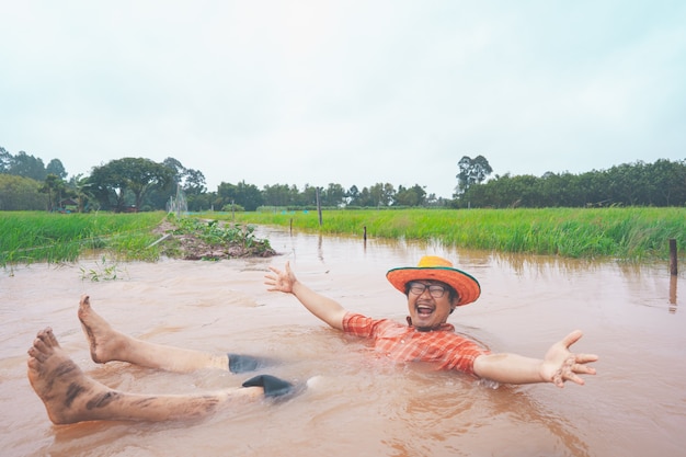 Farmer playing and joyful in heavy flood in rice field of rural or countryside