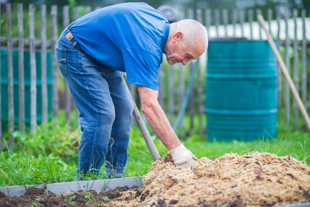 写真 農夫は庭に作物を植えるために土を準備する 耕地 庭園の概念 床の列で育つ農業植物