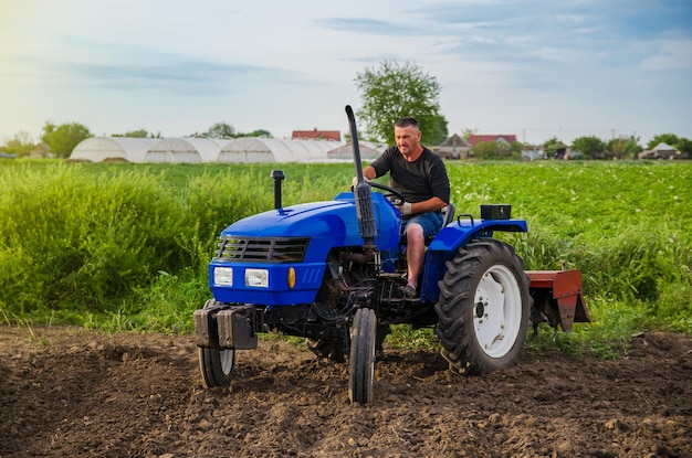 L'agricoltore guida un trattore attraverso il campo fresatura del terreno lavoro nel campo e preparazione